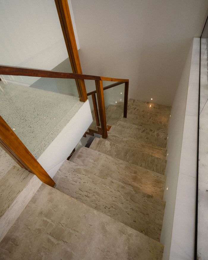 Luxurious marble staircase with wooden railing in a modern interior setting.